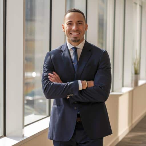 Man in a suite smiling at the camera, who is inside an office building.